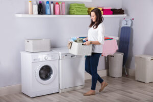 A person standing next to a washing machine in a laundry room.