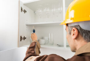 A man wearing a yellow hard hat indoors. He is dressed in workwear.