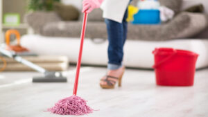a person cleaning the floor with a mop. They are wearing footwear and casual clothing. The activity is taking place indoors.